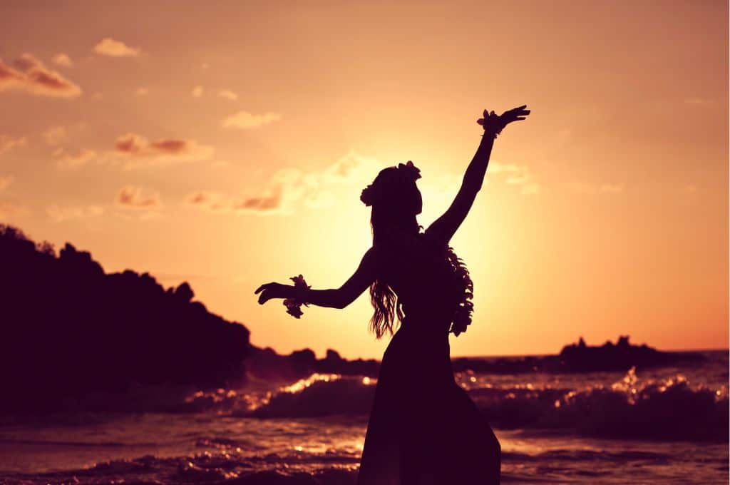 hula dancer dancing at sunset on a beach - are hawaiian luaus worth it