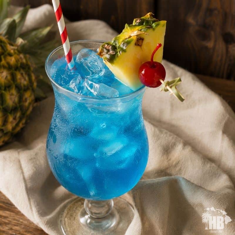 Blue Hawaii cocktail served in a hurricane glass with pineapple wedge and cocktail umbrella